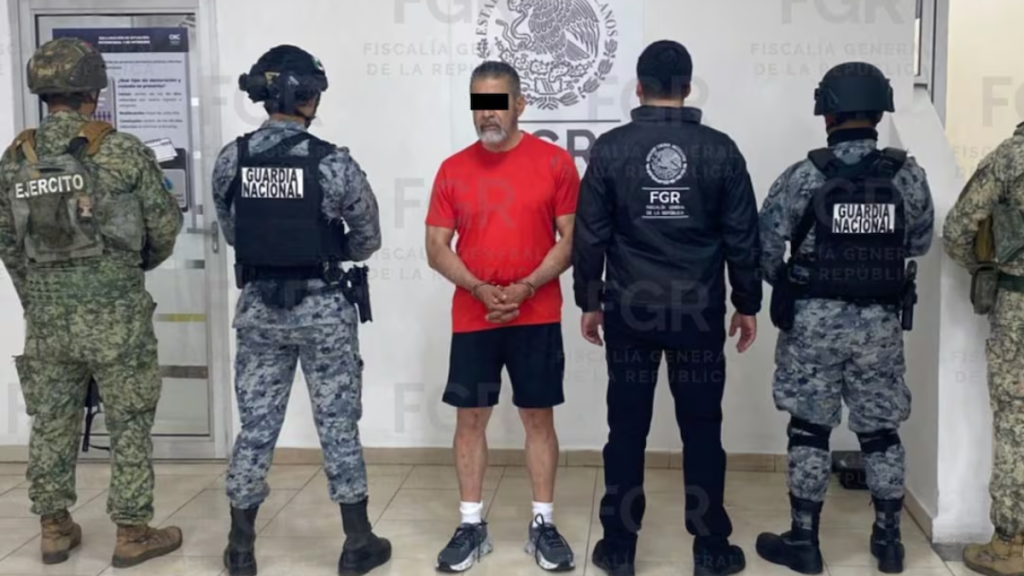Lider-jesus-ricardo-puente-pago-millones - Vecinos Unidos Detainee in a Red Shirt with Hands Bound, Flanked by Uniformed Officers from Guardia Nacional and Fgr in a Hallway. - Vecinos Unidos
