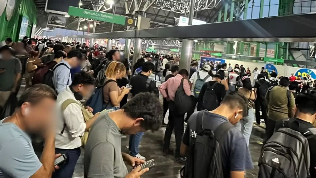 Crowded Indoor Transit Hall with Many People Standing in a Long Line, Some Looking at Phones. - Vecinos Unidos